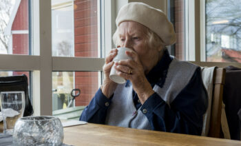 Äldre kvinna dricker kaffe