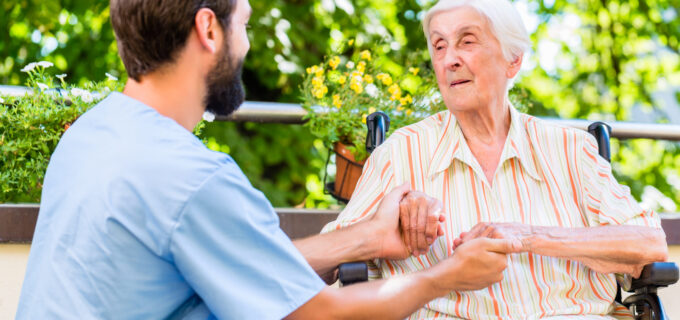 Undersköterska håller en äldre dam i händerna