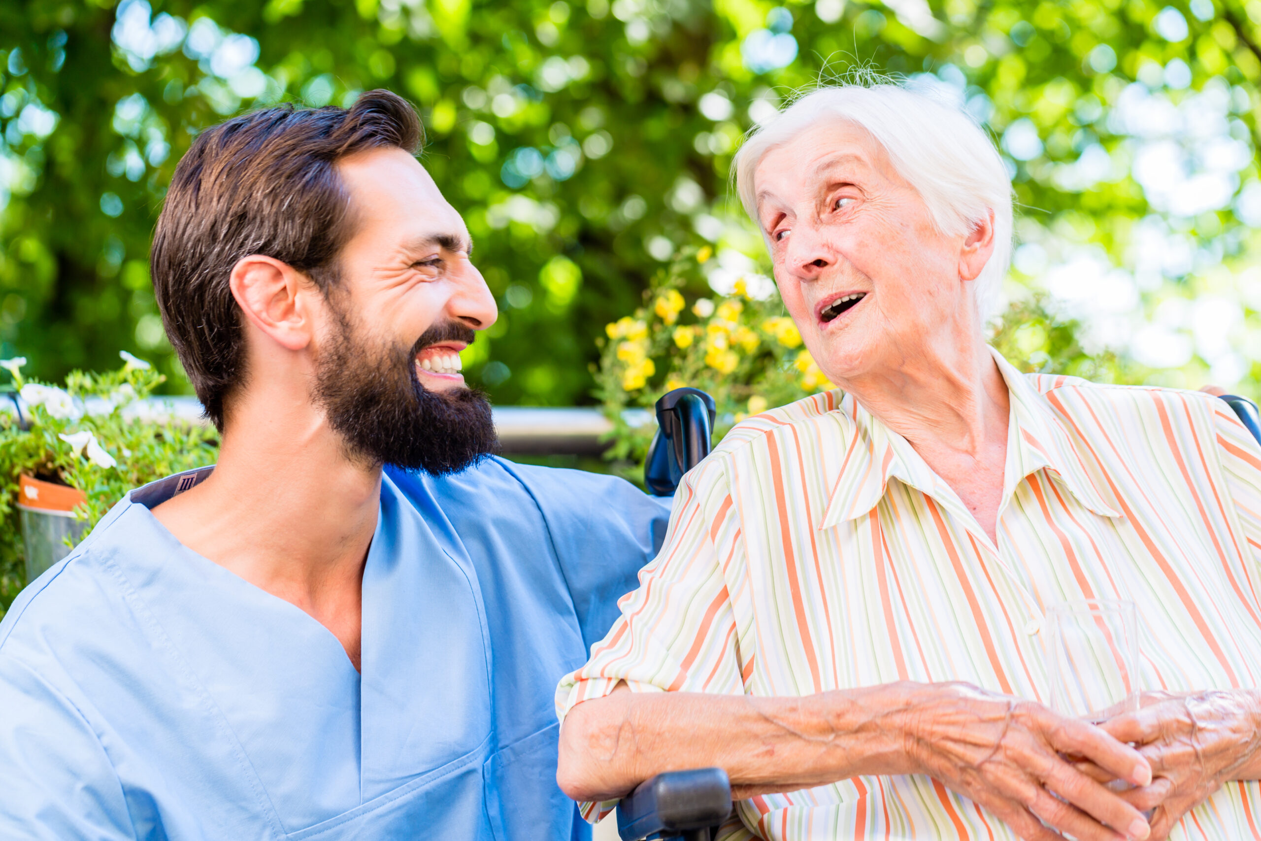 Manligt vårdbiträde skrattar med en äldre kvinna