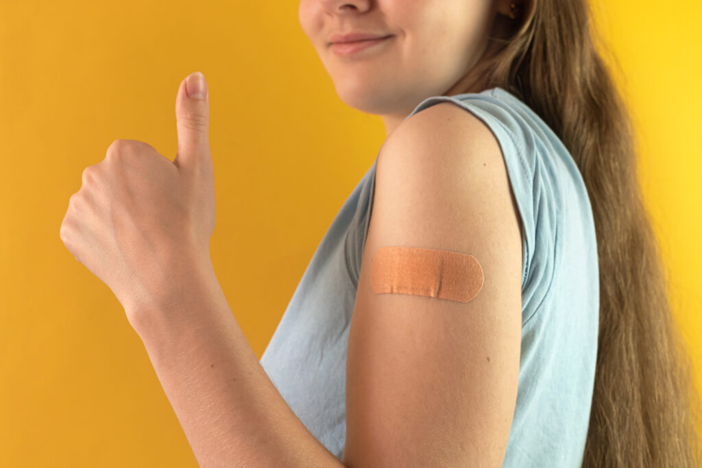 Glad tjej med plåster på armen, som fått vaccination
