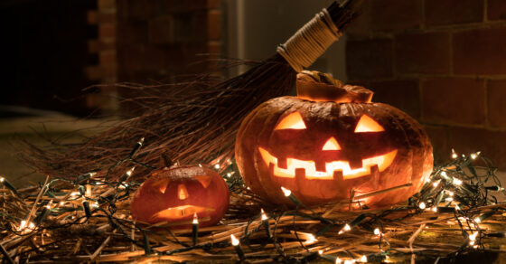 Halloweenpumpa och en kvast liggandes på en ljusslinga