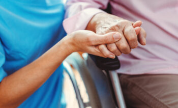 Vårdpersonal håller en äldres hand