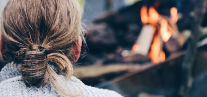 Siluett av en man bakifrån som sitter framför en eld.