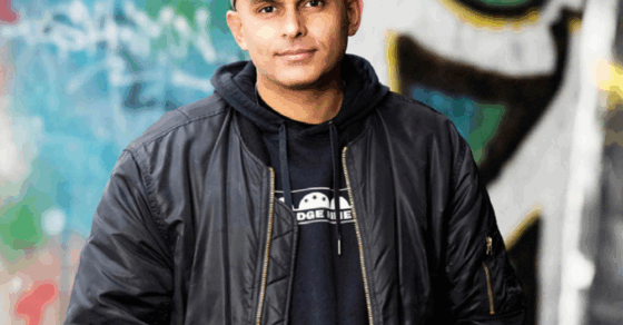 Kille med bomberjacka och keps står framför en betongvägg med grafitti.