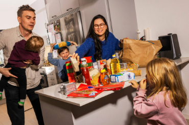 Familj som står vid en bänk med matvaror på. Foto: MSB