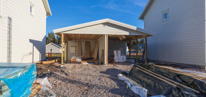 Två nybyggda hus där det byggs garage med med carport.