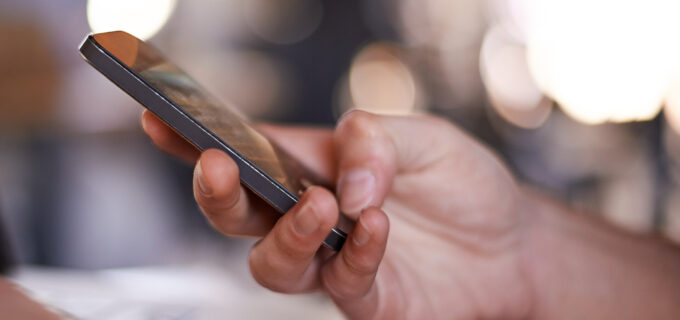 Hand som håller i en mobiltelefon.