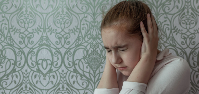 En flicka som blundar och håller för öronen. På bilden ligger texten viktiga telefonnumemr.