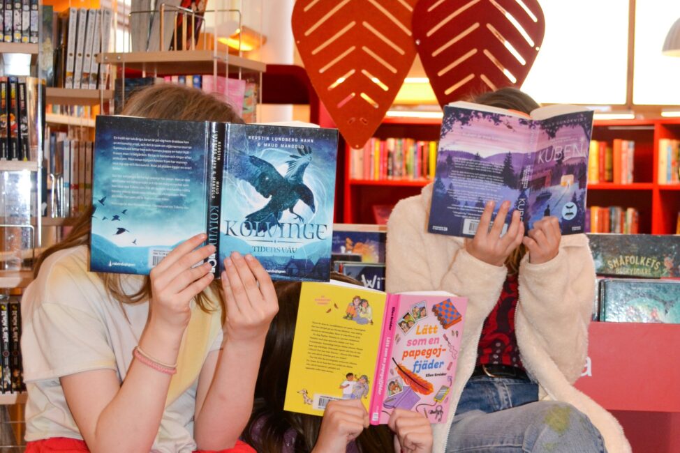 Tre barn med varsin bok som döljer ansiktet