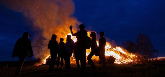 Siluetten av ungdomar framför en brasa.