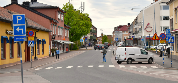 Åsgatan i Hedemora med bilar på parkeringen vid sidan av vägen och människor på trottoarerna.