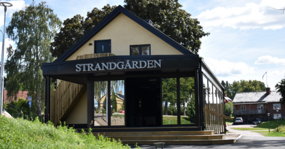 En ljusgul byggnad med ett stort öppningsbart glasparti, ovanför glaset står texten Strandgården.