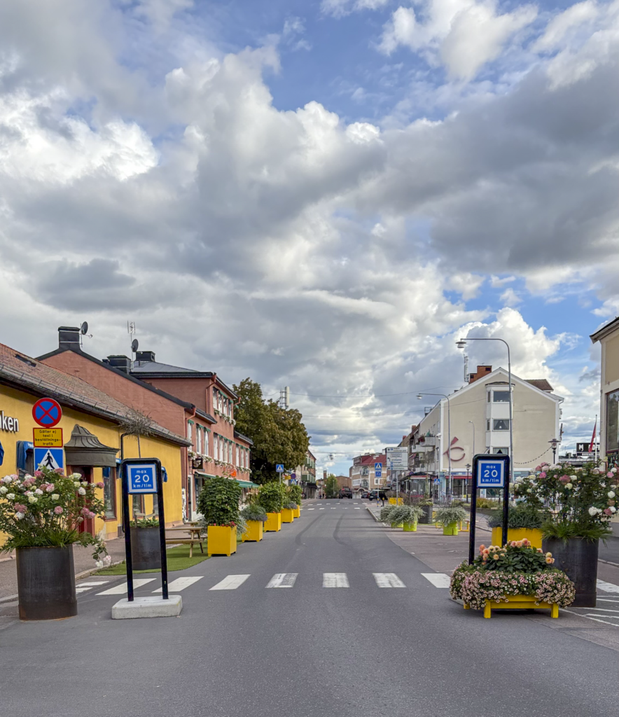 Sommargata i Hedemora med gula bänkar, bord och planteringar.